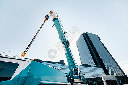 玻璃现代建筑附近带吊钩的蓝色起重机升降机构 起重机和液压升降机高达 120 米活动电梯折叠力量车辆机械技术生长天空科技图片