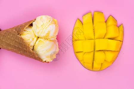 粉红色背景的华夫蛋筒中的芒果味冰淇淋球 粉红色背景中带冰淇淋的成熟芒果芒果水果异国情调粉色味道锥体食物牛奶甜点图片