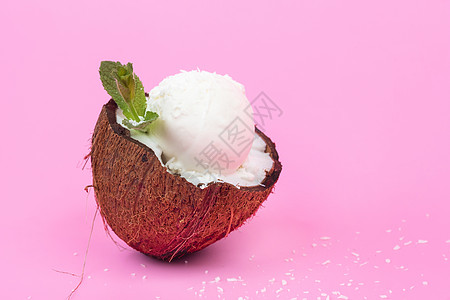 粉红色背景上用薄荷叶装饰的新鲜椰子半香草冰淇淋球叶子食物热带甜点味道异国产品情调水果树叶图片