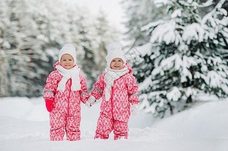 两个穿红西装的小双胞女 站在寒雪的冬季森林里公园婴儿双胞胎新年西装白帽子家庭姐妹孩子们朋友们图片