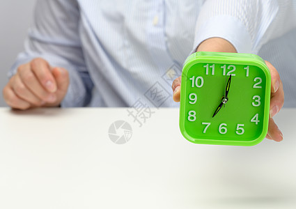 女人的手握着绿方闹钟 早上7点时钟显示 早起吧 开始吧女性手臂绿色警报手指戒指商业工作手表小时图片
