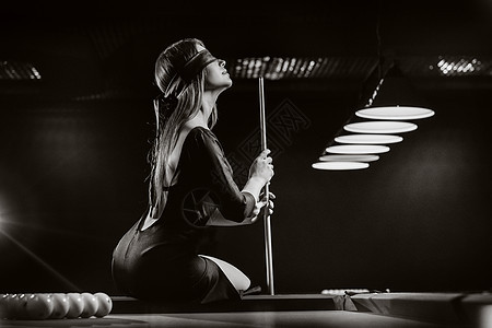 一个戴着眼罩 手里拿着球杆的女孩坐在台球俱乐部的桌子上 俄罗斯台球 黑白照片爱好玩家枕头水池眼睛娱乐绿盖口袋照片游戏图片