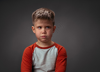 悲哀的男孩看着相机 学龄前孩子表达情感 孤立在灰色背景上 冲突概念 向右复制空间图片