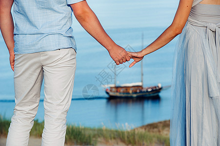 一对相爱的情侣站在沙丘的海滩上 背景是波罗的海和一艘船 一对情侣在立陶宛尼达的海滩特写海岸国家地平线旅行夫妻恋人假期天空财富蓝色图片