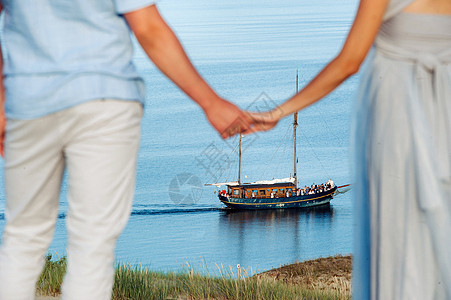 一对相爱的情侣站在沙丘的海滩上 背景是波罗的海和一艘船 一对情侣在立陶宛尼达的海滩特写财富海岸线海岸帆船天空夫妻家庭旅行奢华公园图片