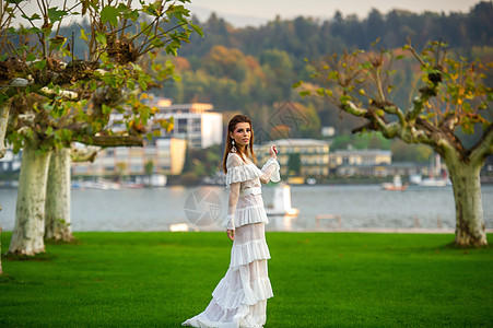 穿着白婚礼服的新娘 位于奥地利城镇的一个公园中 日落时有大树形象青年婚礼婚纱建筑学天空裙子女士魅力空气图片