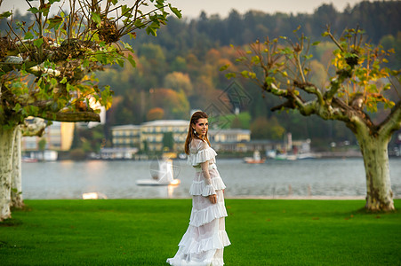穿着白婚礼服的新娘 位于奥地利城镇的一个公园中 日落时有大树空气树木形象村庄长裙城市女士婚纱青年建筑学图片