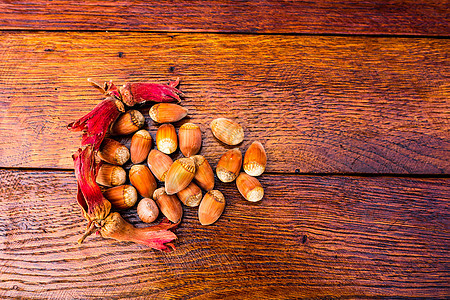 木制桌上新鲜成熟的红桃子森林红色营养树叶坚果榛子小吃叶子种子棕色图片