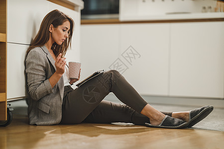 她的第一次杯在早晨电话厨房女士活动休闲沉思享受社交水平电子邮件图片