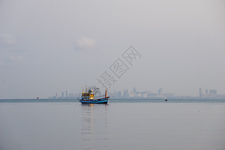 一艘小渔船停靠在岸边的渔捞站后方钓鱼海洋旅行船运蓝色货运海滩天空港口反射图片