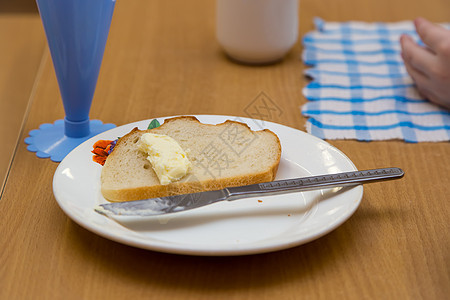 贴上一块白面包 上面有黄油和白色盘子上的木头图片