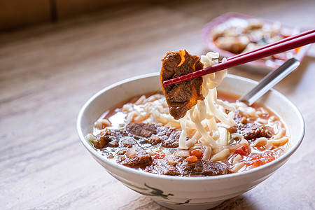 台湾食物牛肉面  台湾拉面餐 在明亮的木桌上的碗里放着番茄酱汤 著名的中式食物 特写 顶视图 复制空间肉汤面条桌子勺子拉面美食筷子洋葱食背景