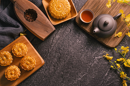 中秋节传统食品概念  黑石板桌上的美丽月饼 配有茶 糕点模具 花 顶视图 平躺 复制空间节日桌子食物茶壶杯子兰花托盘石板盘子木头图片