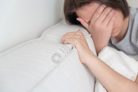 坐在床上抱着枕头的悲伤女人卫生失眠女性寝具保健疼痛房间头发疾病女孩图片