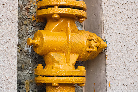 房屋墙上的黄色水管金属力量活力管子技术工程液体气体螺栓阀门图片