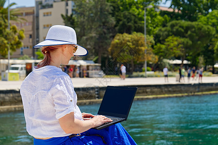 女商业自由职业者坐在海边的码头上 在笔记本电脑上工作技术潮人屏幕电子邮件购物互联网女士女孩网络业者图片