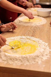 几个人的手在敲打桌上的面粉 用面粉混合一个生蛋白色厨师厨房糕点营养木板食谱食物蛋黄勺子图片