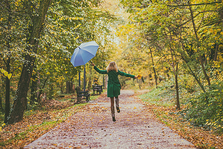 带着雨伞和秋叶的快乐女人图片