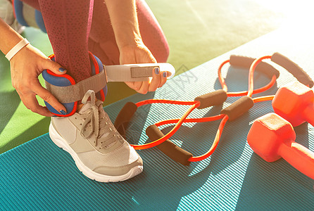 女人在健身 健康和健身概念运动前先戴脚踝护身衣 把哑铃放在垫子上娱乐女孩理疗锻炼训练重量身体活动肌肉体操图片