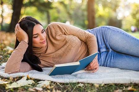 女子在公园看书 秋天享受太阳休闲女性毛衣阳光沉思毯子黑发阅读草地图片