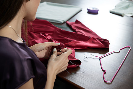 在裁缝工作室或餐饮店缝制红裙子的 美丽的年轻女服装匠剪裁设计师人体女裁缝手工职场女士工作职业磁带图片