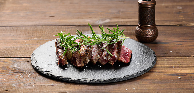 在黑板上切成碎片的炸牛肉肉 鲜有熟食度 美味牛排迷迭香炙烤肋眼黑色木板牛扒胡椒食物横幅草本植物图片