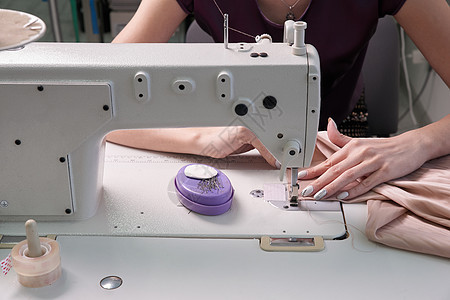 在现代美食店裁缝室使用缝纫机的裁缝匠裙子爱好材料手指衣服工艺工厂剪裁接缝工人图片