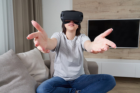 快乐的年轻女人在室内玩 VR 眼镜虚拟现实概念与年轻女孩玩耳机护目镜和复制空间游戏视频女性微笑女士长椅成人模拟器工具乐趣图片