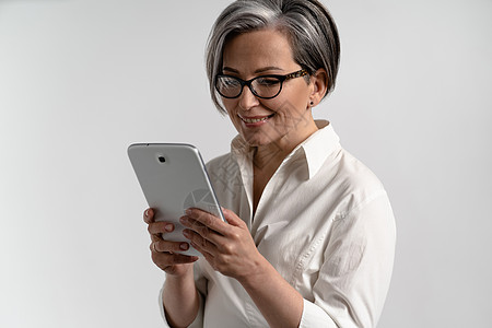 一位身穿白衬衫 戴着眼镜的灰发高级女性使用数字平板电脑的画像 老年人使用白色背景隔离的垫浏览网上购物的技术互联网设备用户药片视频图片