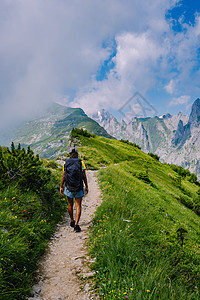 一个背着背包的女人站在山顶 这个女孩去美丽的地方旅行 到达目标 的山脊 瑞士的 Kreuzberge悬崖闲暇游客自由草地假期旅游图片