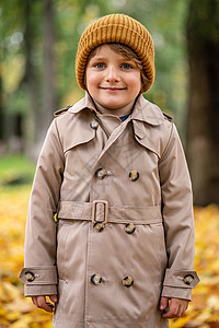 一个穿着秋大衣和帽子的可爱小男孩 站在秋天街上 对着摄影机笑得可爱极了闲暇衣服微笑幸福男性公园家庭冒充乐趣季节图片