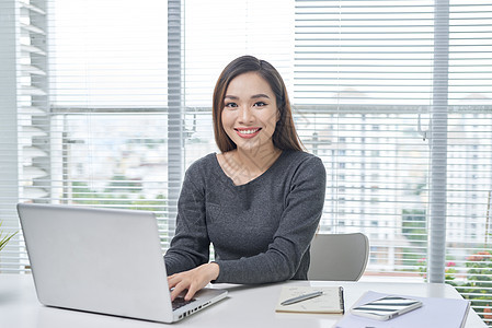 一位美丽的女士坐在桌子上 办公室生活 工作的地方成人互联网经理微笑电脑女性笔记本快乐图片