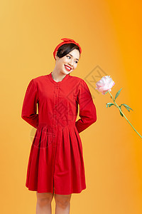 充满欢欣鼓舞的亚洲年轻女性 她满身是玫瑰 站在橙色背景之上眼睛展示礼服女士成人魅力红色女孩裙子工作室图片