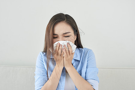 照片上一位生病的年轻女士坐在沙发上吹破她的流鼻涕组织女性女孩流感白色医疗疾病喷嚏黑色图片