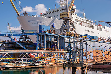 在船坞干码头的大型船舶修理起重机造船工作血管码头工人船运船厂绘画检测背景
