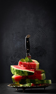 一连串熟熟的红西瓜片 夹在一个金属板块中 卡在一把大刀里图片