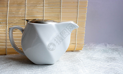 白色陶瓷茶壶 有铁盖的白陶瓷茶壶 站在白色背景上图片
