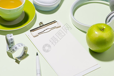 健康的概念 喷水器 茶叶和苹果 在糊面彩色背景上图片