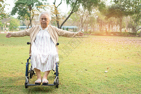 亚洲老年或老年老妇人病人在轮椅上锻炼 在公园里享受新鲜快乐 健康强健的医疗理念图片