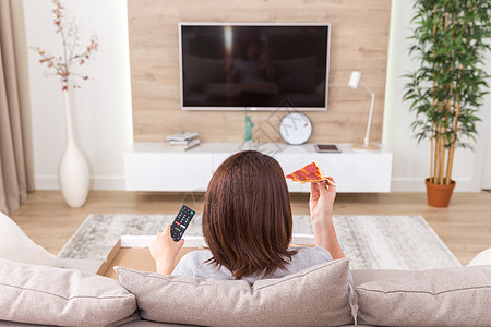 单身妇女吃披萨和看电视枕头女孩情绪化手表花费长椅成人食物女性孤独图片