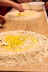 几个人的手在敲打桌上的面粉 用面粉混合一个生蛋营养食谱混合物烹饪美食桌子木板橙子勺子披萨图片