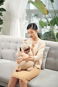 女人和玩具狗坐在沙发上青少年微笑青年朋友动物女孩拥抱女士情感玩具熊图片