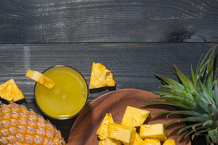 黑木桌上菠萝果和菠萝果杯的顶端视图黄色饮食果汁凤梨叶子液体白色水果玻璃食物图片