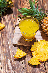 玻璃里新鲜的菠萝汁 木本底有菠萝果水果食物黄色绿色凤梨叶子白色饮食果汁液体图片