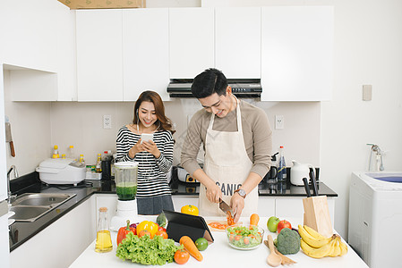 亚裔妇女使用手机 而男子则做饭图片