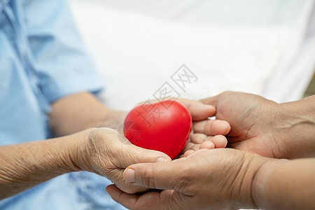 亚洲老年或老年老妇人病人在护理医院病房的床上手握红心 健康强健的医疗理念帮助女士卫生保健家庭国家生活心脏病学世界慈善事业图片