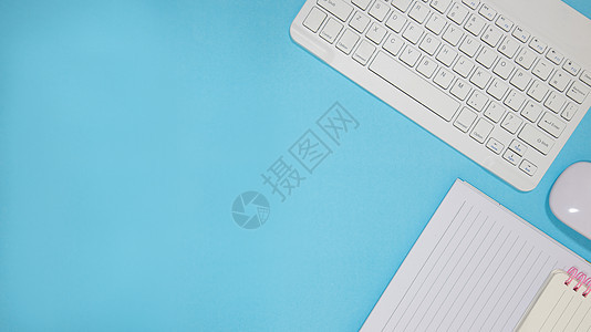 办公桌 配有一套五颜六色的用品 蓝色空白记事本 杯子 笔 个人电脑 弄皱的纸 蓝色背景的花 文本的顶视图和复制空间字帖笔记纸床单图片