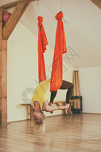 从事空中瑜伽的妇女灵活性训练肌肉姿势运动健身房女士体操反重带子图片