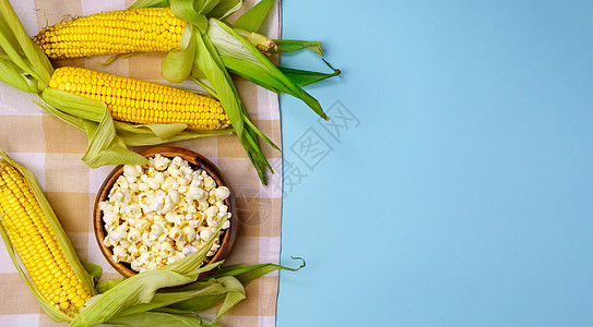 玉米在鳕鱼上 爆米花在蓝色背景 主题农业 玉米种植 收获黑色娱乐棒子小吃流行音乐营养盐渍食物电影剧院图片