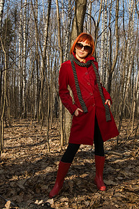 穿着红外套和墨镜的漂亮女孩女孩女士太阳镜衣服靴子红色季节女性森林图片